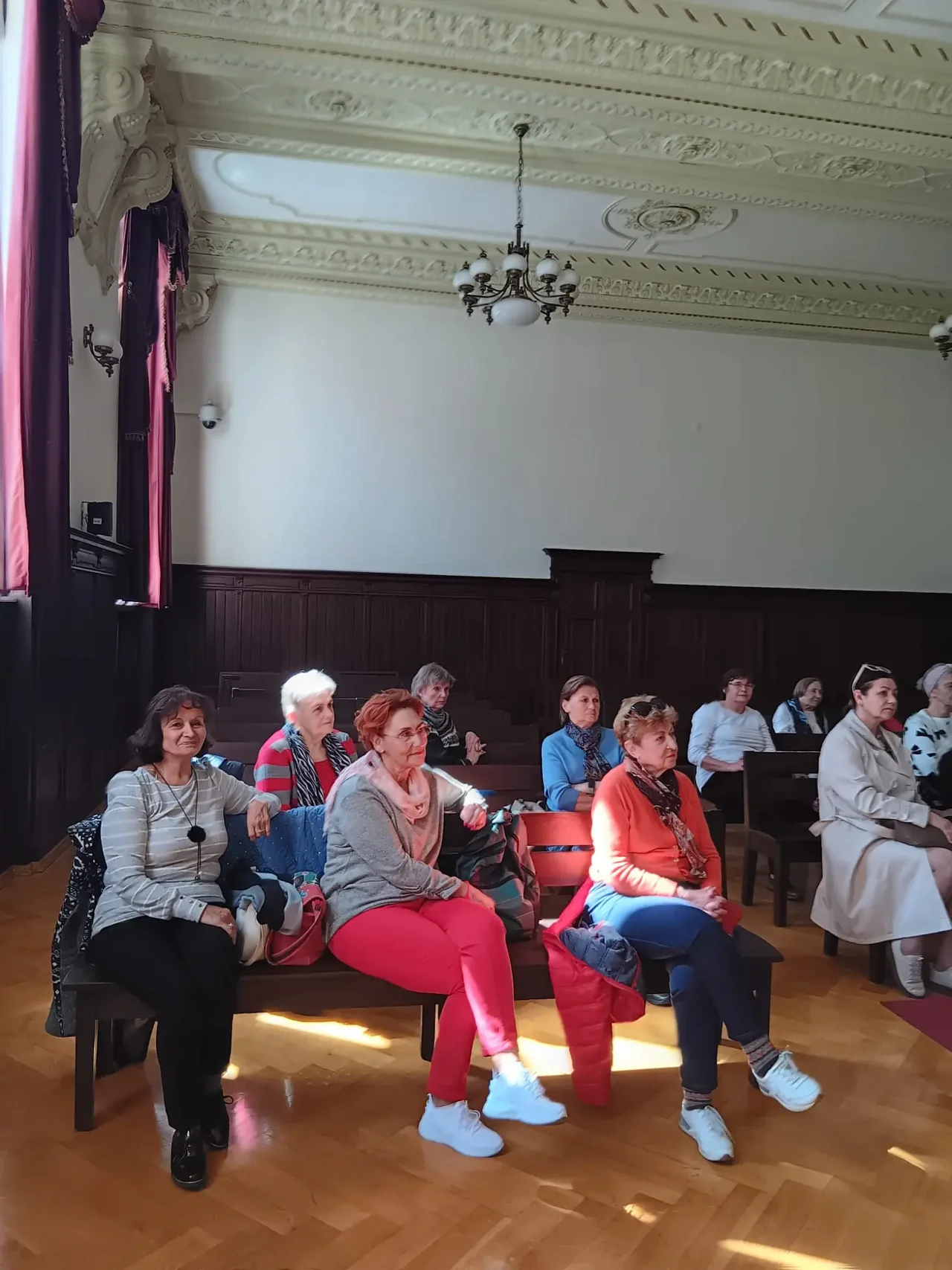 Grupa seniorów siedzących w sali sądowej podczas wykładu