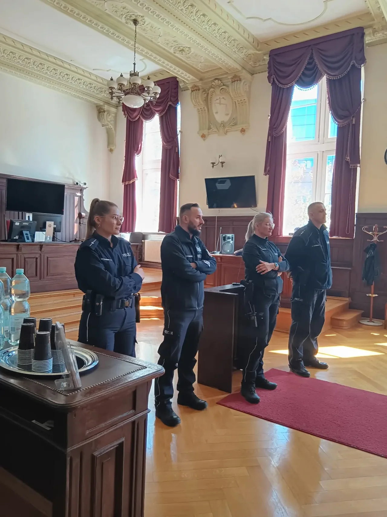 POlicjanci na sali sądowej prowadzący prelekcje o bezpieczeńtwie