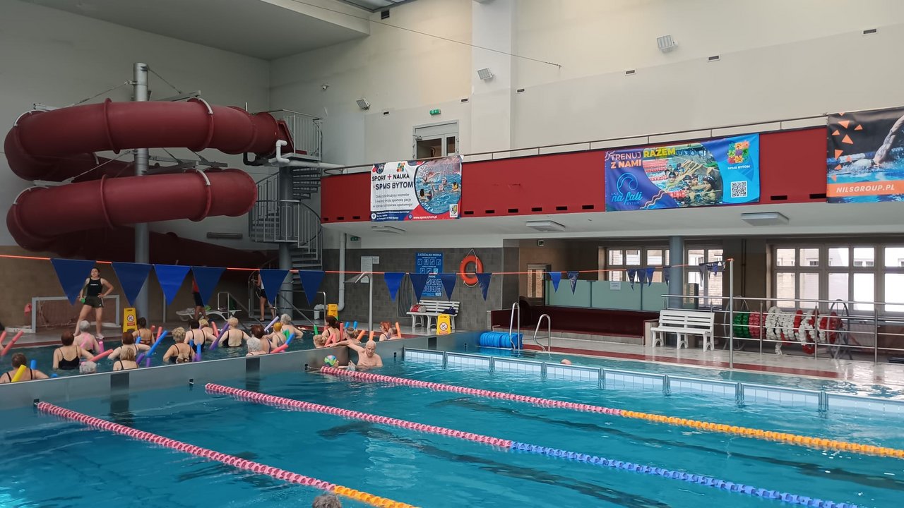 Grupa seniorów UTW Bytom podczas zajęć aquaaerobiku z makaronami piankowymi na basenie SPMS Bytom