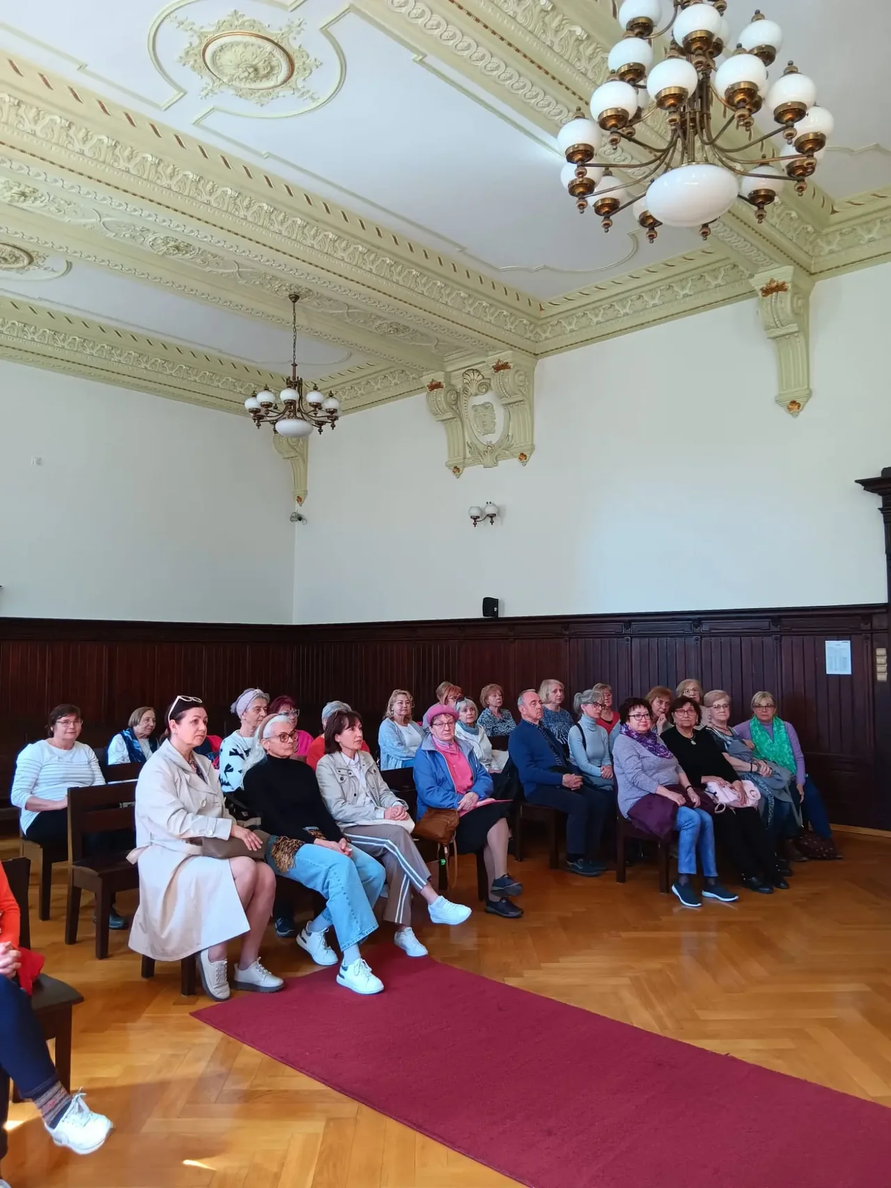 Grupa seniorów siedzących w sali sądowej podczas wykładu